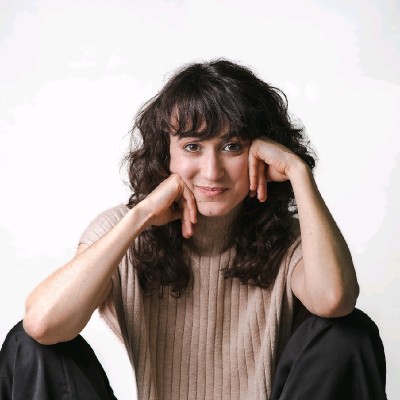 Foto de Beatriz Alves, aluna do curso de UX Design, mulher branca com cabelo longo, camiseta bege, e com as mãos no rosto.