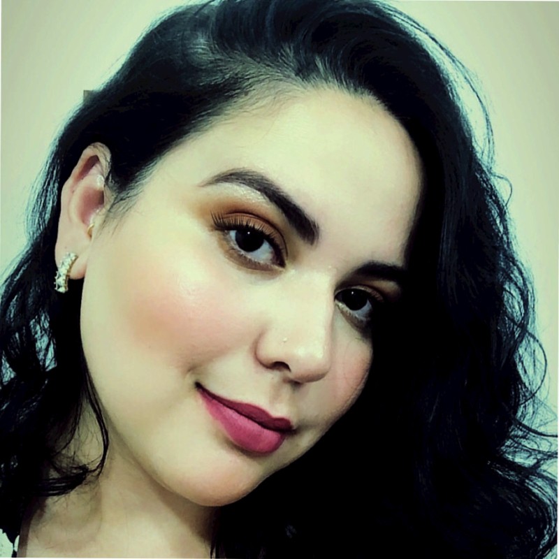 Foto de Bruna Vichi, aluna do curso de Design de Conteúdo Acessível, uma mulher branca com cabelos pretos longos e lisos, com o rosto levemente de lado, maquiada e usando batom.
