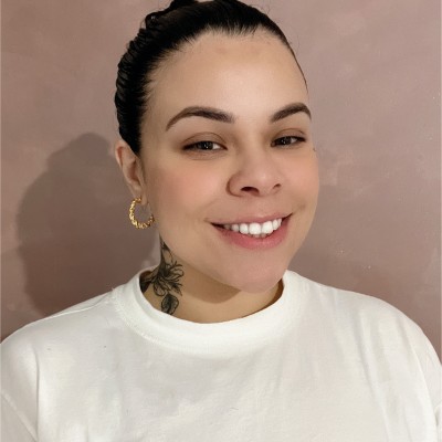 Foto de Sonia Araujo, aluna do curso de UX Design, mulher branca com cabelo bem curto, camiseta branca e uma tatuagem no pescoço.
